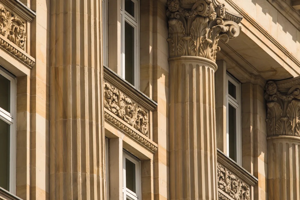 Decorated stone column with Corinthian chapter and floral reliefs on a classic building.