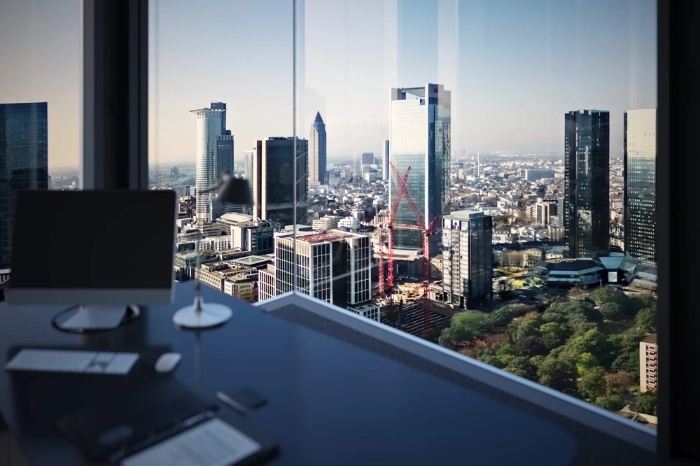 Blick aus einem Bürofenster auf eine Stadt mit modernen Hochhäusern und einem Kran, Bäume im Vordergrund.