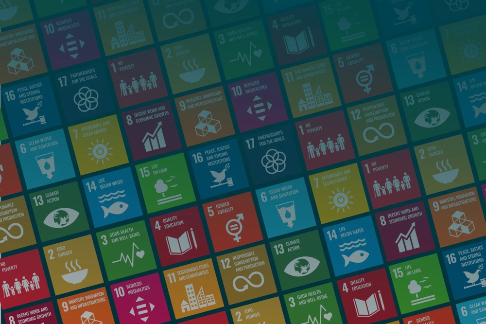 Colorful tile-style illustration featuring the 17 United Nations Sustainable Development Goals (SDGs), including poverty reduction, health, education, gender equality, clean water, renewable energy, climate action, and peace, arranged in a diagonal grid pattern
