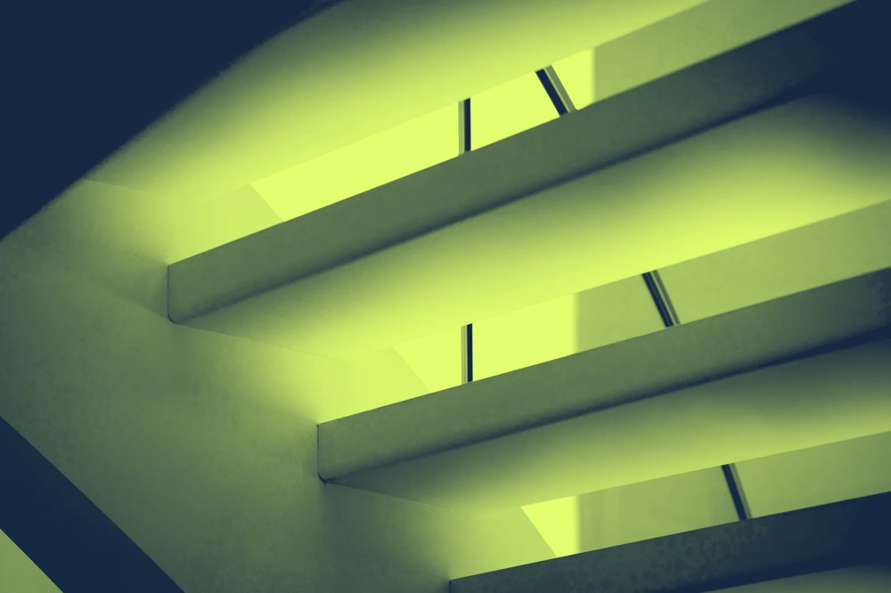 Grüne, diagonale Streben und Lichtstreifen formen ein abstraktes, geometrisches Muster.