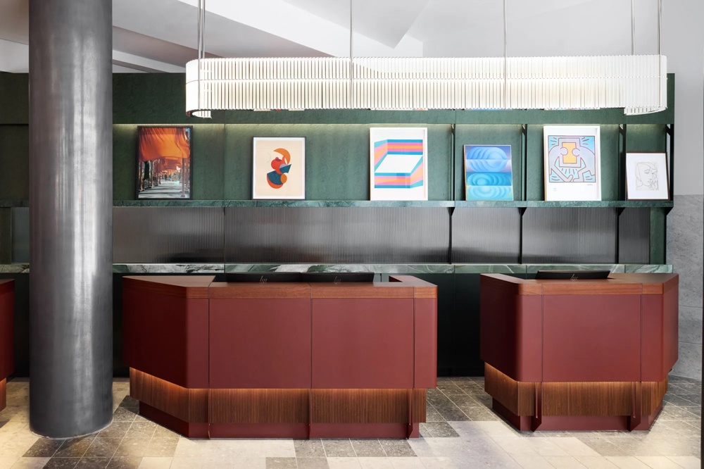 Moderne Rezeption mit dunkelroten Theken, grüner Wand und abstrakter Kunst an der Wand.