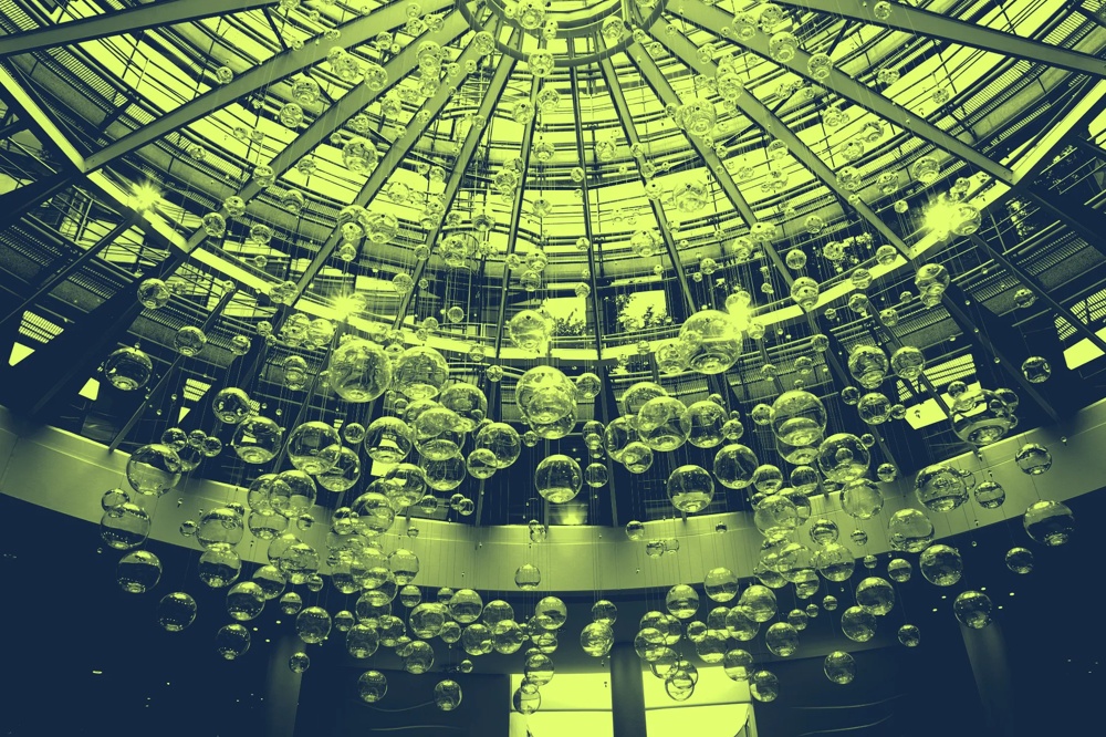 Glaskuppel mit hängenden Glasblasen, die von Sonnenlicht beleuchtet werden.