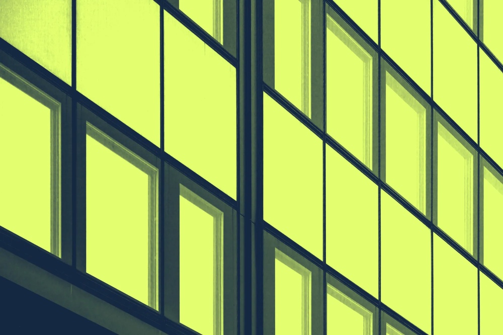 Gelbe Fensterfassade mit geometrischem Muster und dunklen Rahmen.