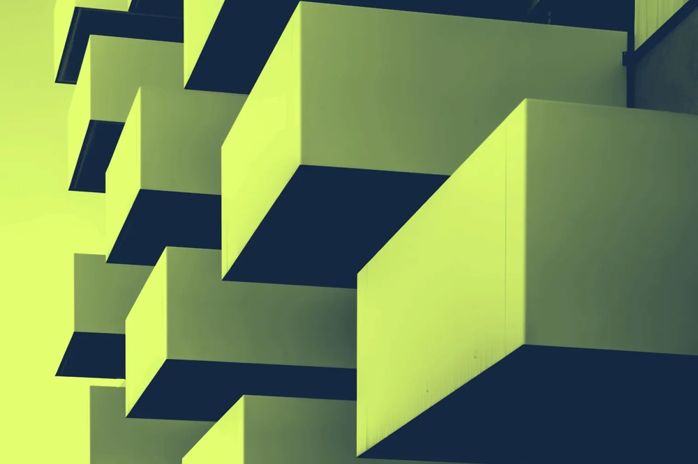 Übereinander gestapelte, rechteckige Balkone eines modernen Gebäudes in gelb-grüner Tönung.