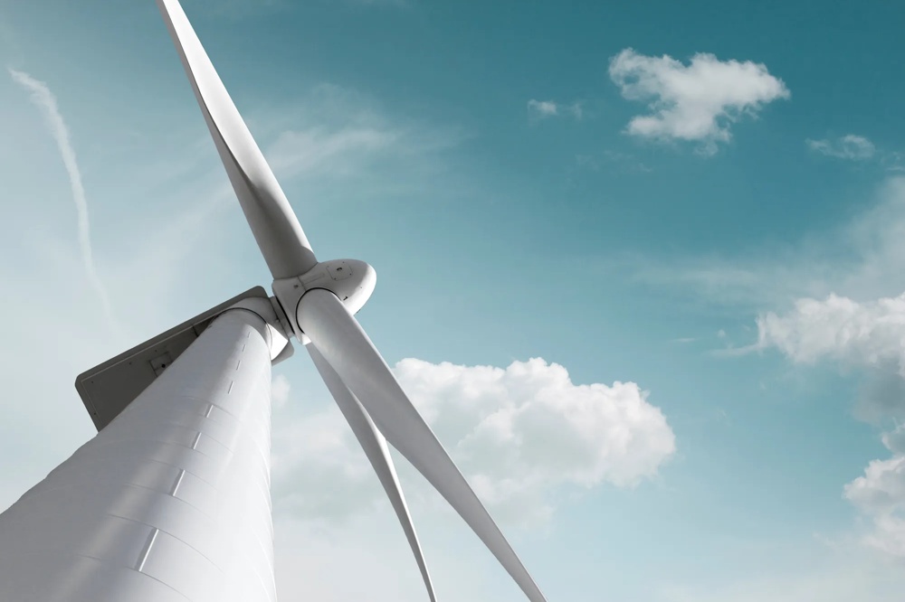 Nahaufnahme einer Windkraftanlage vor blauem Himmel mit weißen Wolken, Symbol für erneuerbare Energie