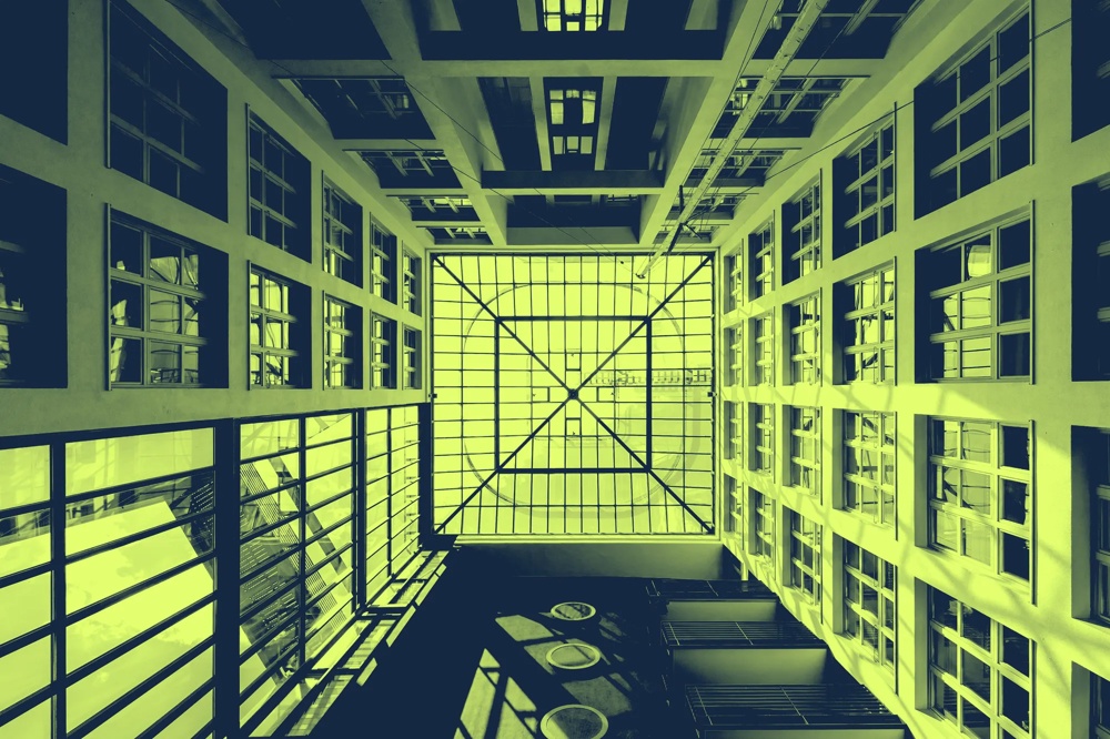 Blick nach oben in einen modernen Innenhof mit Glasdach und symmetrischen Fenstern, in Grün- und Gelbtönen gefärbt.