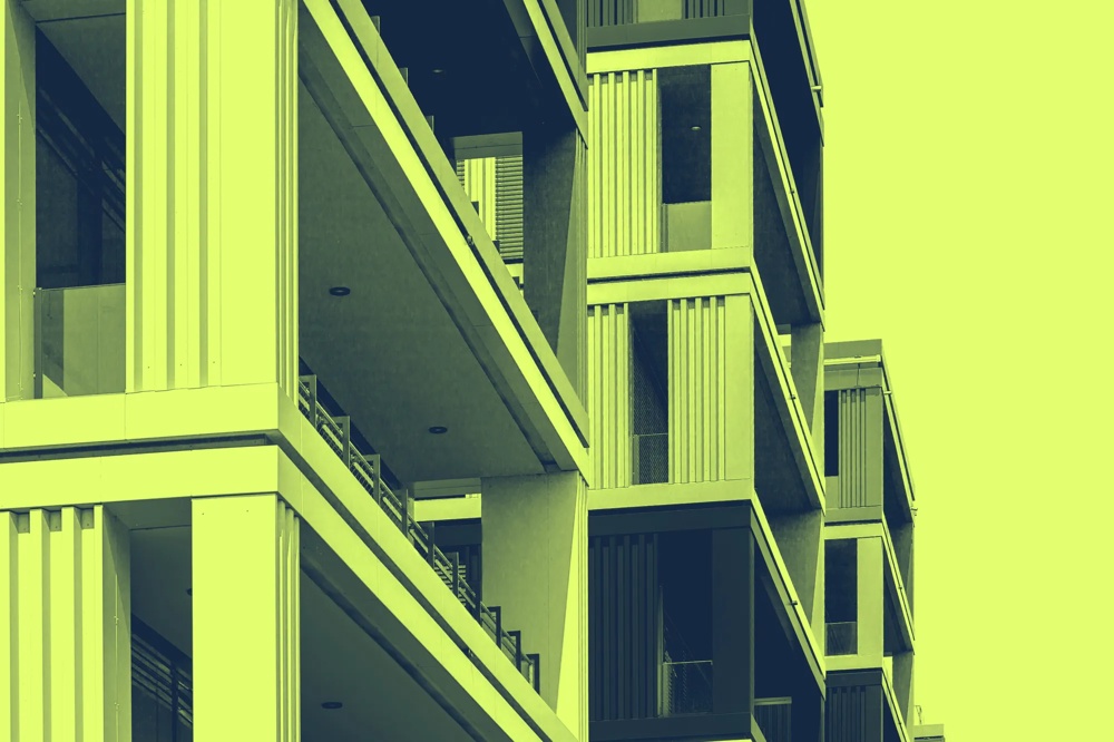 Moderne Gebäude mit Balkonen und vertikalen Linien in gelb-grünem Farbton.