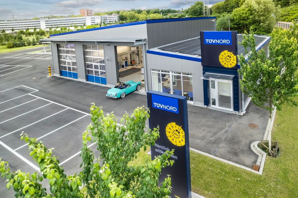 Parkplatz mit einer Autowerkstatt von oben, die vom TÜV Nord betrieben wird