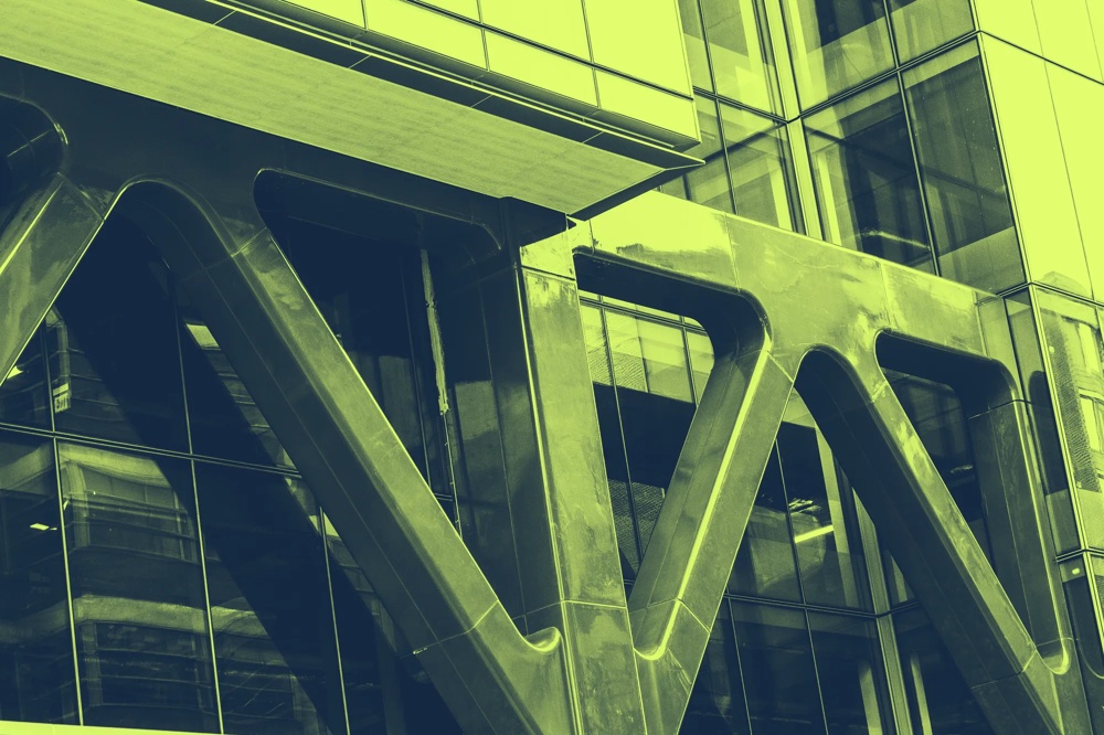 Moderne Glasfassade mit großen, diagonal verlaufenden Metallträgern.