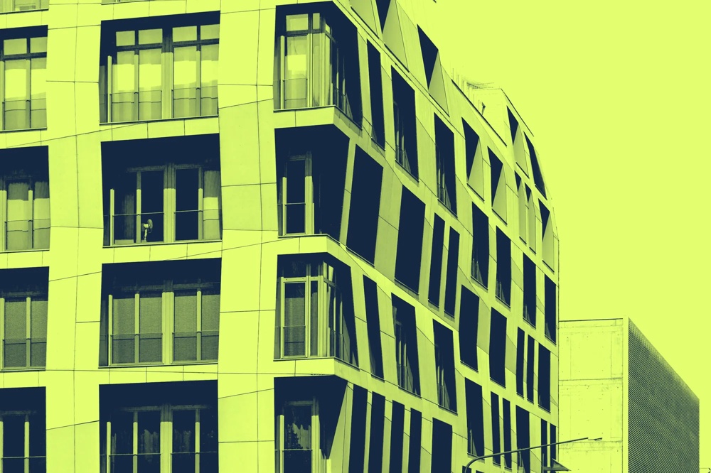 Modernes Gebäude mit unregelmäßigen Fenstern in gelb-grünem Farbton, seitliche Ansicht.