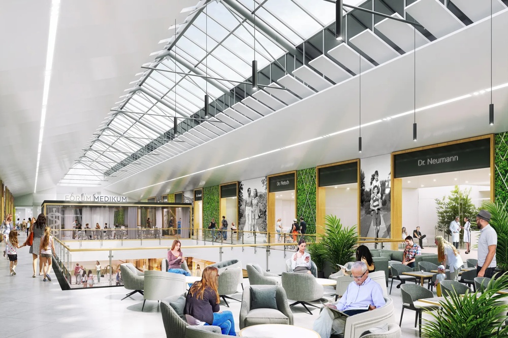 Menschen gehen durch ein modernes Einkaufszentrum mit Glasdach und grünen Wänden.