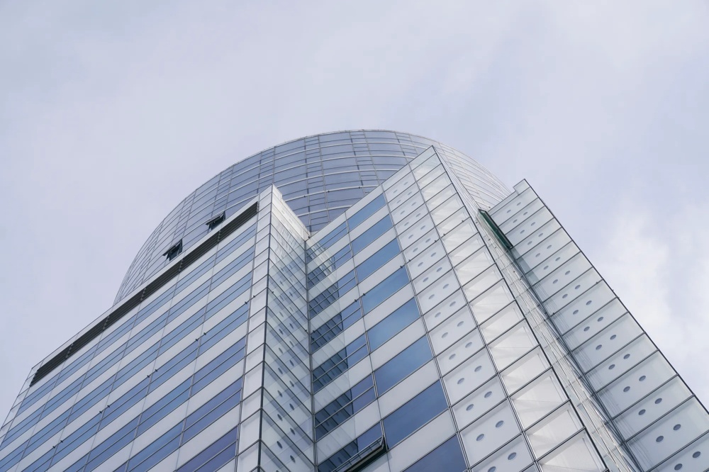 Modern, tall building with a glass facade against a cloudy sky.