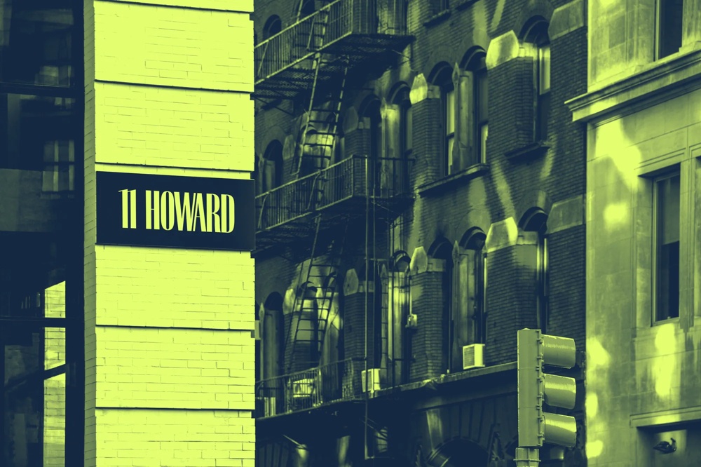 Gebäude mit "11 Howard" Schild, Feuerleiter an Backsteinfassade, Ampel im Vordergrund.