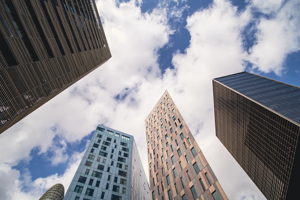 Hohe Gebäude ragen in den Himmel mit weißen Wolken und blauem Himmel im Hintergrund.
