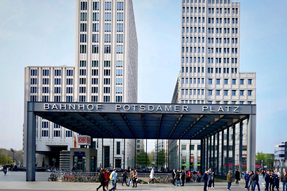 Eingang Bahnhof Potsdamer Platz, moderne Gebäude, Menschen und Fahrräder im Vordergrund.