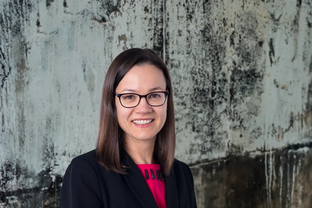 Young woman smiling, wearing glasses and a black blazer