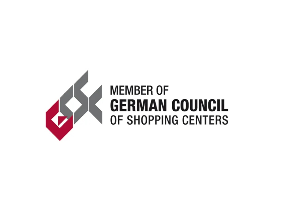 Logo aus ineinandergreifenden geometrischen Formen in Grau und Dunkelrot mit dem Schriftzug „Member of German Council of Shopping Centers" – Branchenverband der Einkaufszentren-Branche.