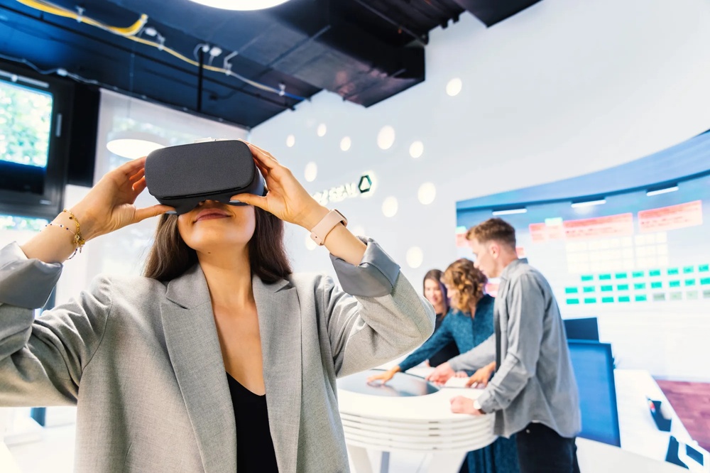 We see a woman in the foreground looking through VR glasses.