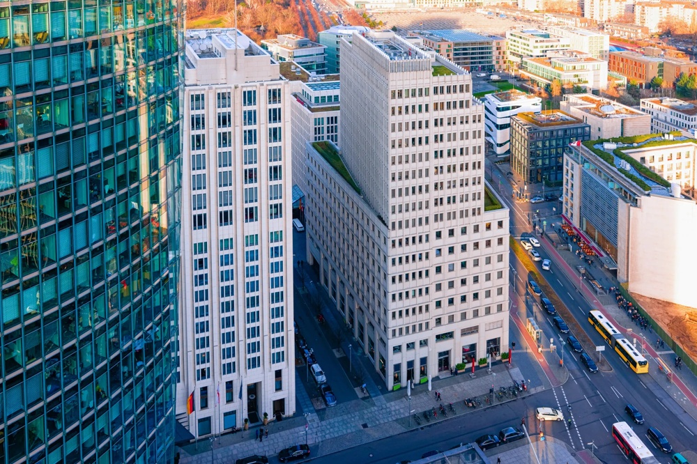 Hochhäuser und Straßen mit Autos und Bussen in einer Stadtlandschaft bei Sonnenuntergang.
