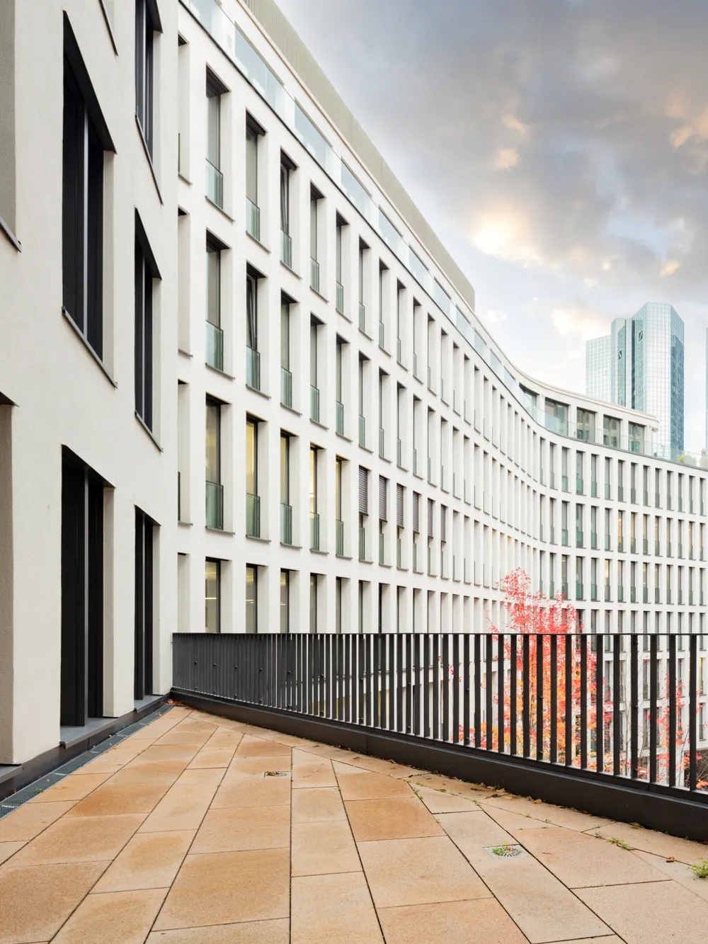 Moderne Gebäude mit Glasfassaden, grauer Himmel, Blick von einer Terrasse mit Geländer.