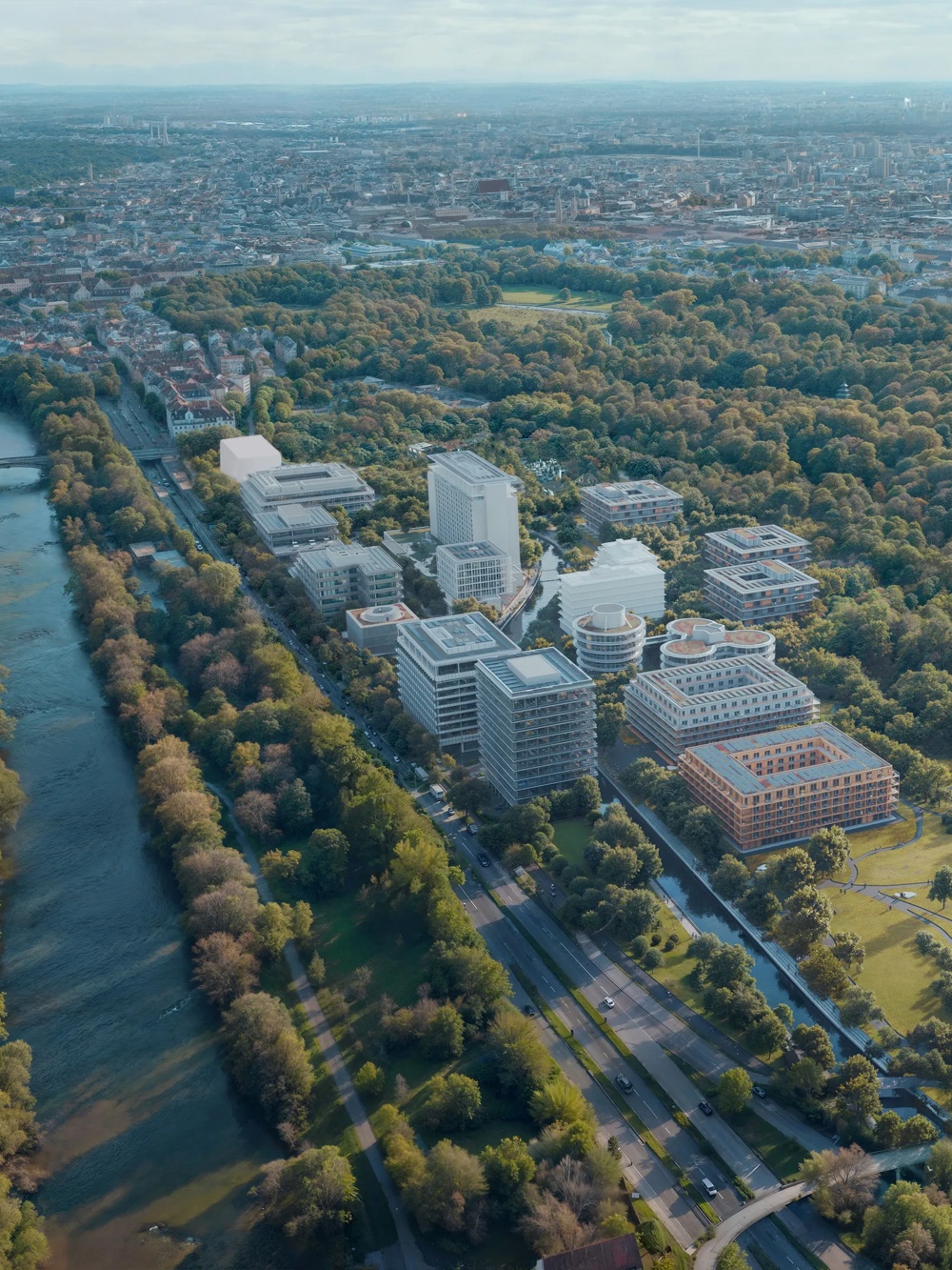 Aerial view of a city with a river, surrounded by trees and modern buildings, in a clear sky.