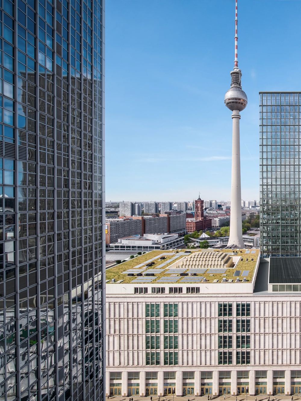 Modern high-rise buildings and a television tower overlook a bustling city street with a clear sky.