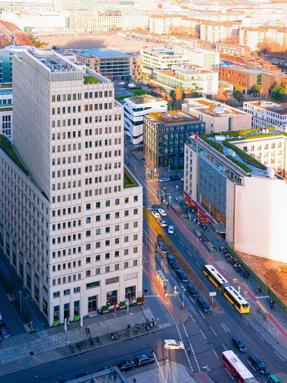 Hochhäuser und Straßen mit Autos und Bussen in einer Stadtlandschaft bei Sonnenuntergang.