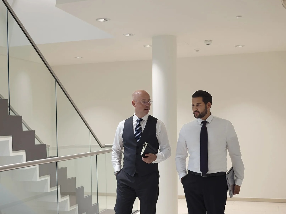 Zwei Männer im Gespräch in einem modernen Bürogebäude in seitliche Ansicht.