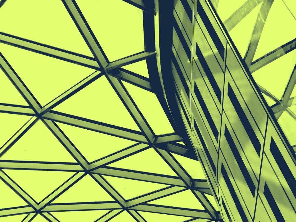 Ein geometrisches Glasdach mit diagonalen Linien in gelbem Licht.