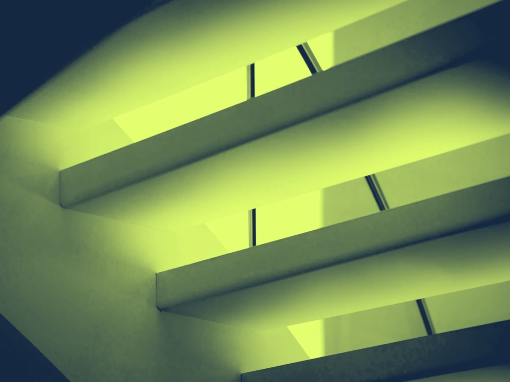 Grüne, diagonale Streben und Lichtstreifen formen ein abstraktes, geometrisches Muster.