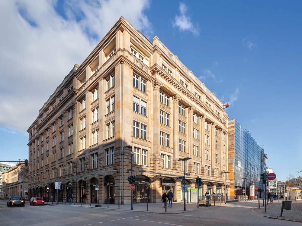 Ein großes, historisches Gebäude mit vielen Fenstern an einer Straßenecke unter blauem Himmel.