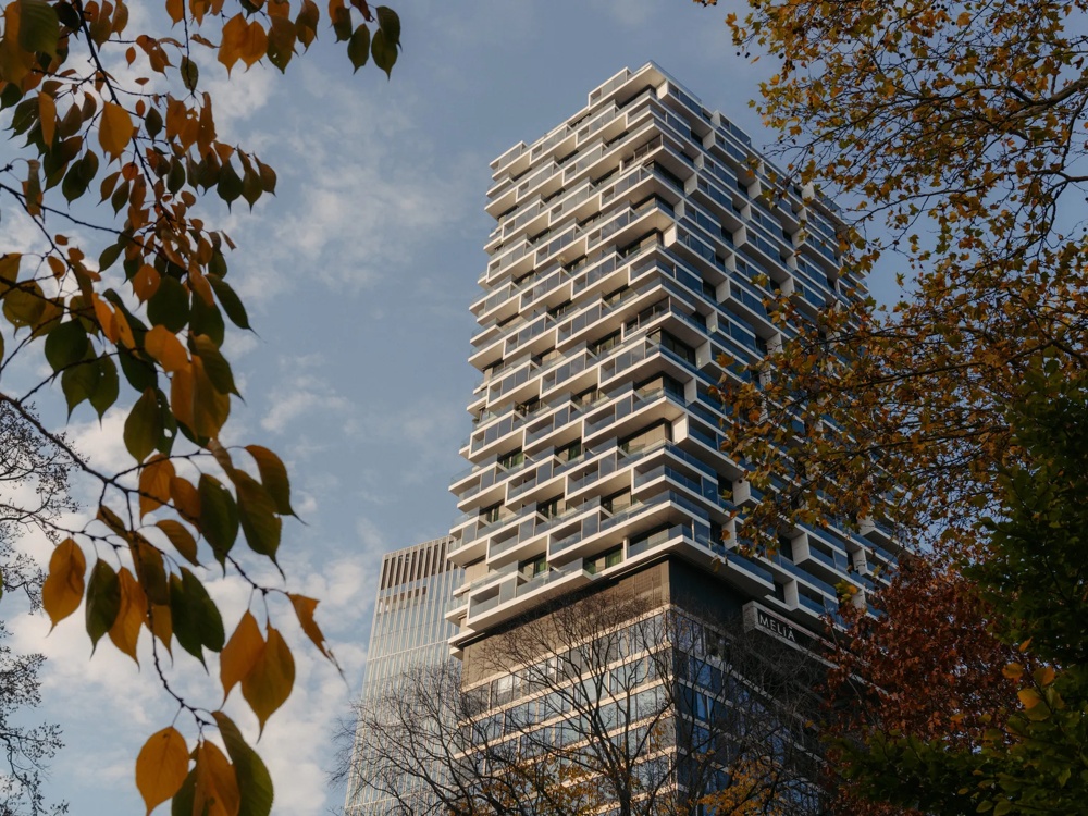 Hochhaus mit markanter Fassade, umgeben von Bäumen.