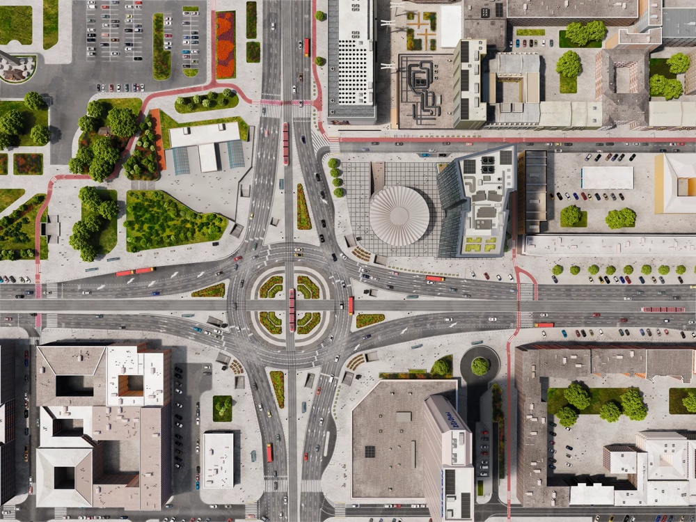 Stadtplan mit Kreisverkehr, umliegenden Gebäuden, Straßen und grünen Parkflächen aus der Vogelperspektive.
