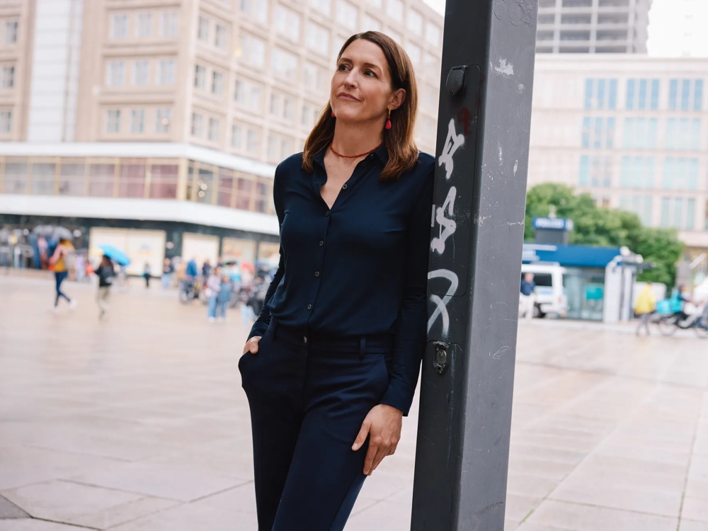 Porträt einer Frau, die auf einem Platz in der Stadt steht.