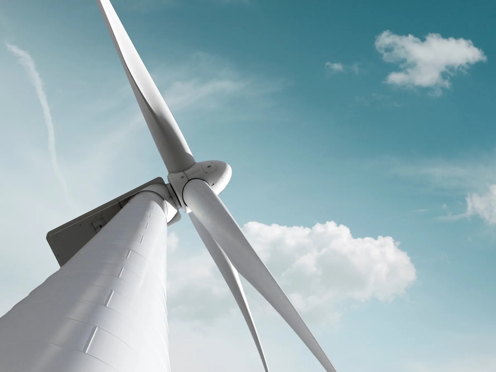 Nahaufnahme einer Windkraftanlage vor blauem Himmel mit weißen Wolken, Symbol für erneuerbare Energie