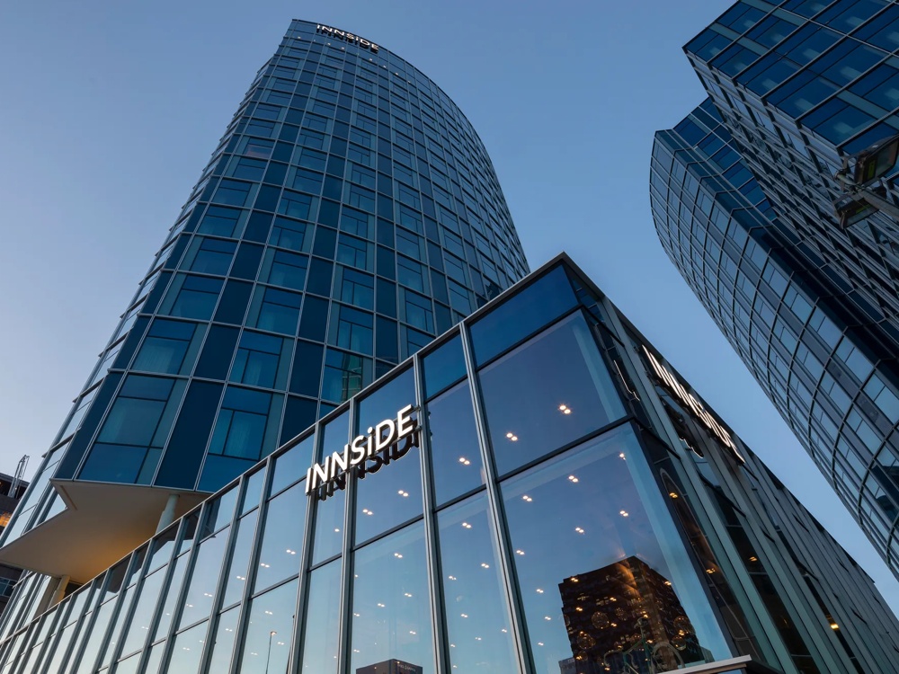 Modernes Hochhaus mit Glasfassade und dem Schriftzug "INNSiDE" bei Abenddämmerung.
