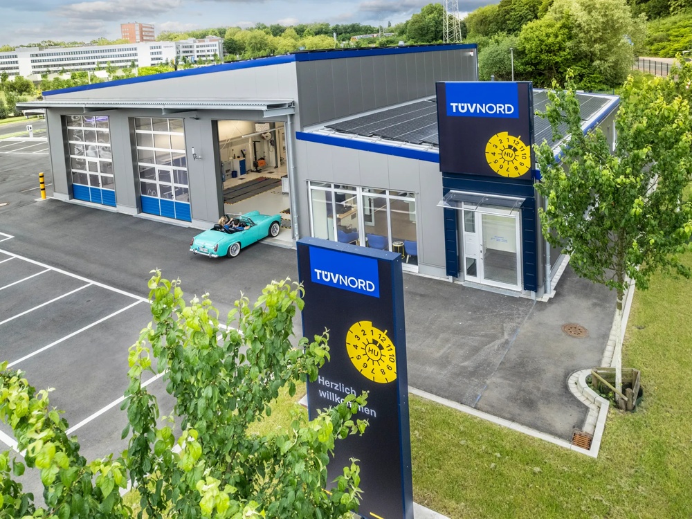 Parkplatz mit einer Autowerkstatt von oben, die vom TÜV Nord betrieben wird