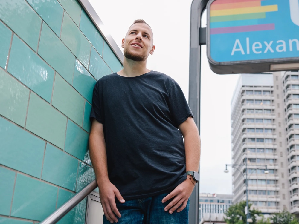 Porträt eines Mannes vor einer U-Bahn-Station mit Stadthochhäusern im Hintergrund.