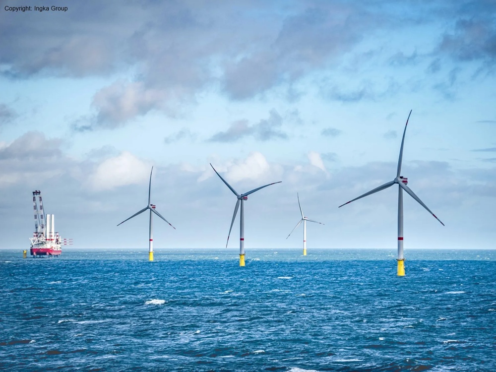Offshore wind farm with five wind turbines and a ship under a cloudy sky.
