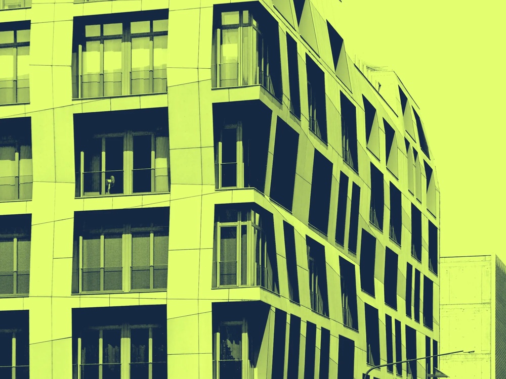 Modernes Gebäude mit unregelmäßigen Fenstern in gelb-grünem Farbton, seitliche Ansicht.
