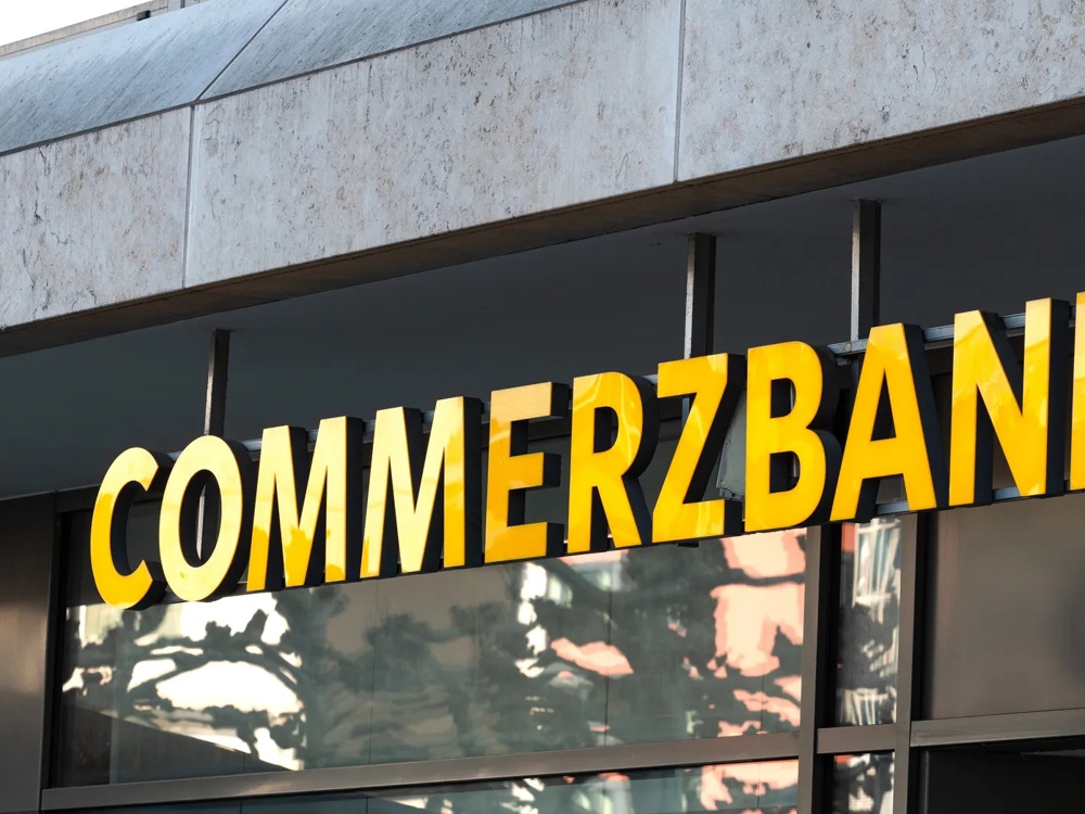Neonschriftzug der Commerzbank an einer Häuserfassade in der Nahaufnahme.