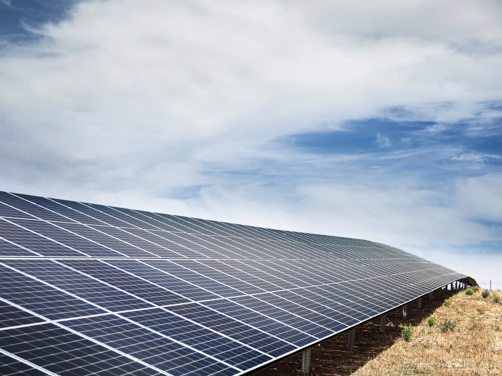 Eine große Solaranlage auf einem Feld unter bewölktem Himmel.