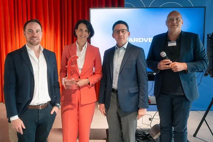 Vier Personen bei einer Preisverleihung, Commerz Real Vorständin Dr. Nicole Arnold Frau im orangefarbenen Hosenanzug hält eine Auszeichnung in Form eines stilisierten „f" – Übergabe des finanzwelt Awards für klimaVest.