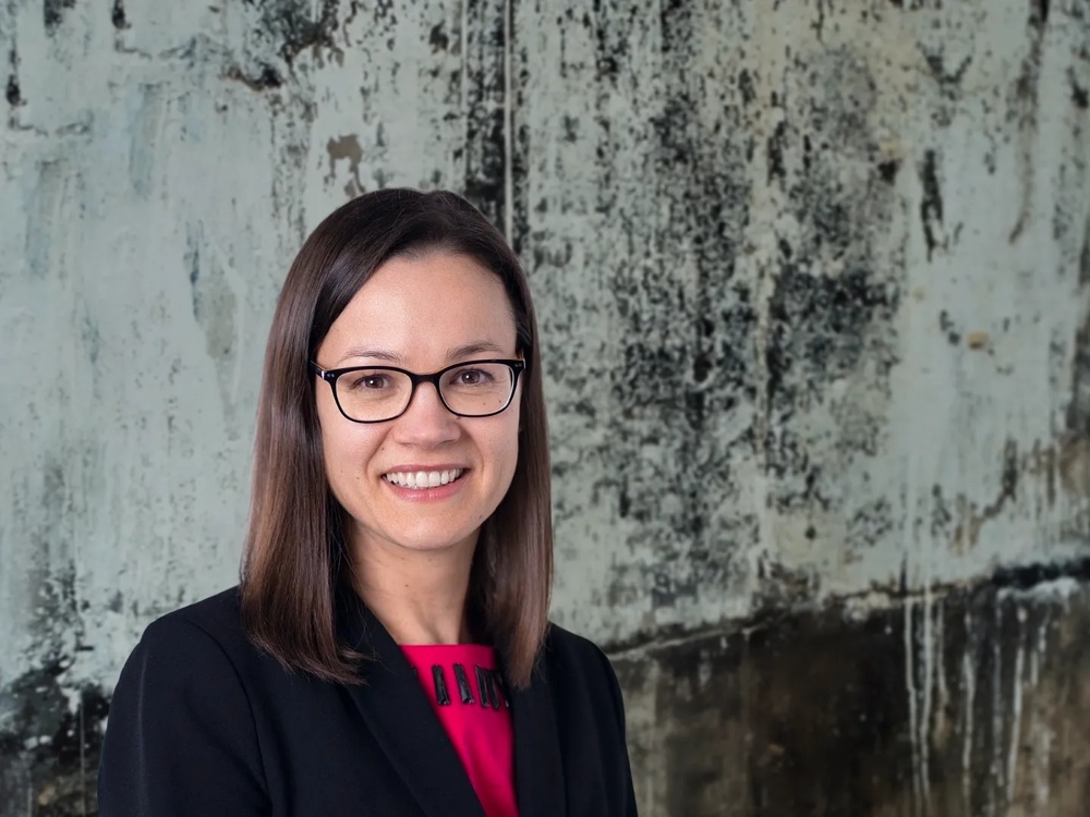Young woman smiling, wearing glasses and a black blazer