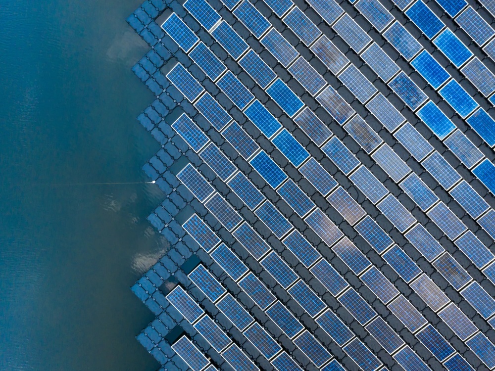 Floating solar panels on a body of water in diagonal arrangement.