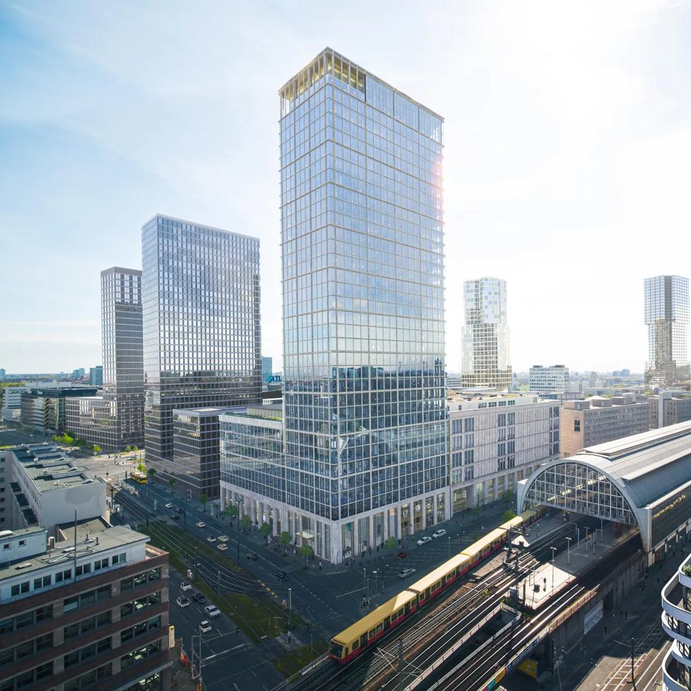 Moderne Stadtansicht mit Hochhäusern, einem großen Bahnhof und einer vorbeifahrenden gelben S-Bahn unter klarem Himmel.
